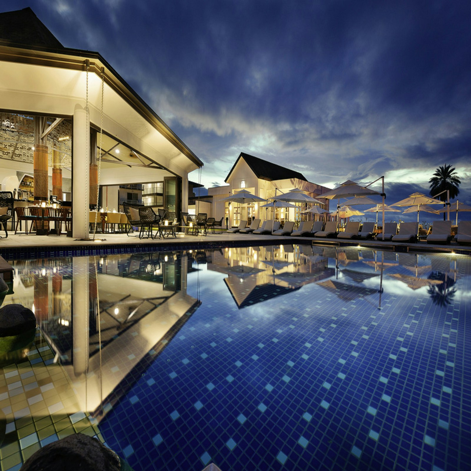 A sunlit resort pool surrounded by palms
